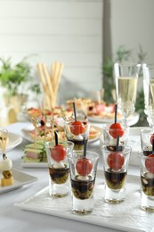 Photo of Many different tasty canapes on white table indoors