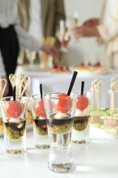 Photo of Many different tasty canapes on white table. People enjoying buffet meals indoors, closeup