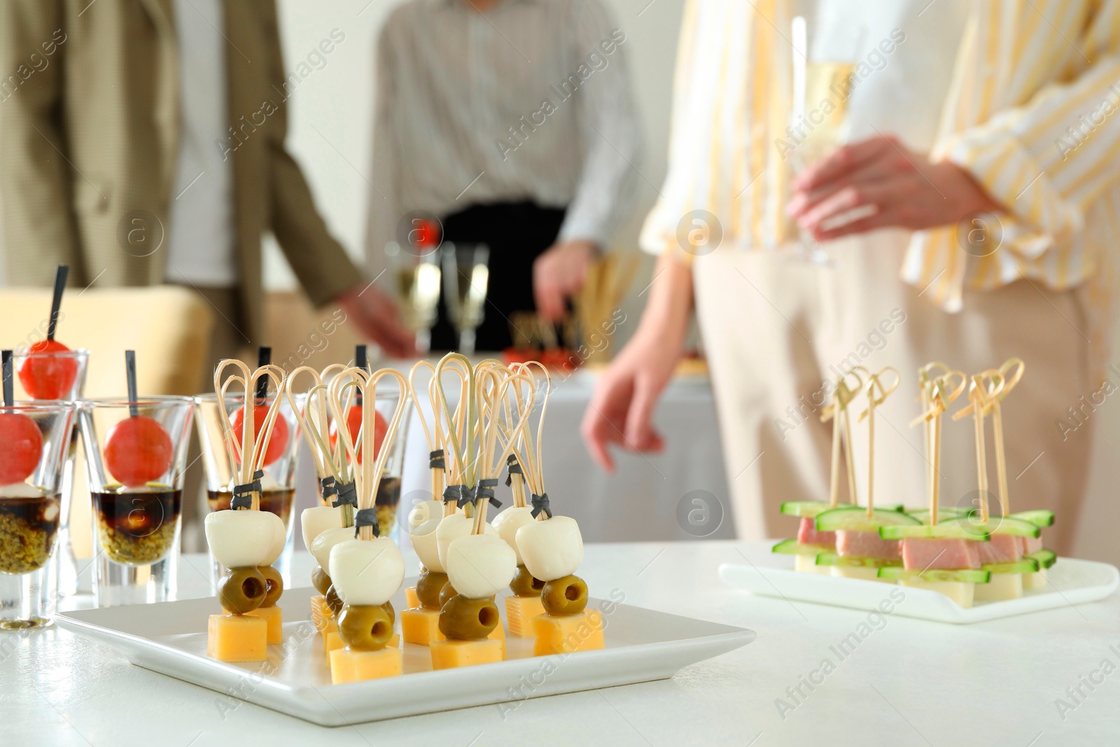 Photo of Many different tasty canapes on white table. People enjoying buffet meals indoors, closeup