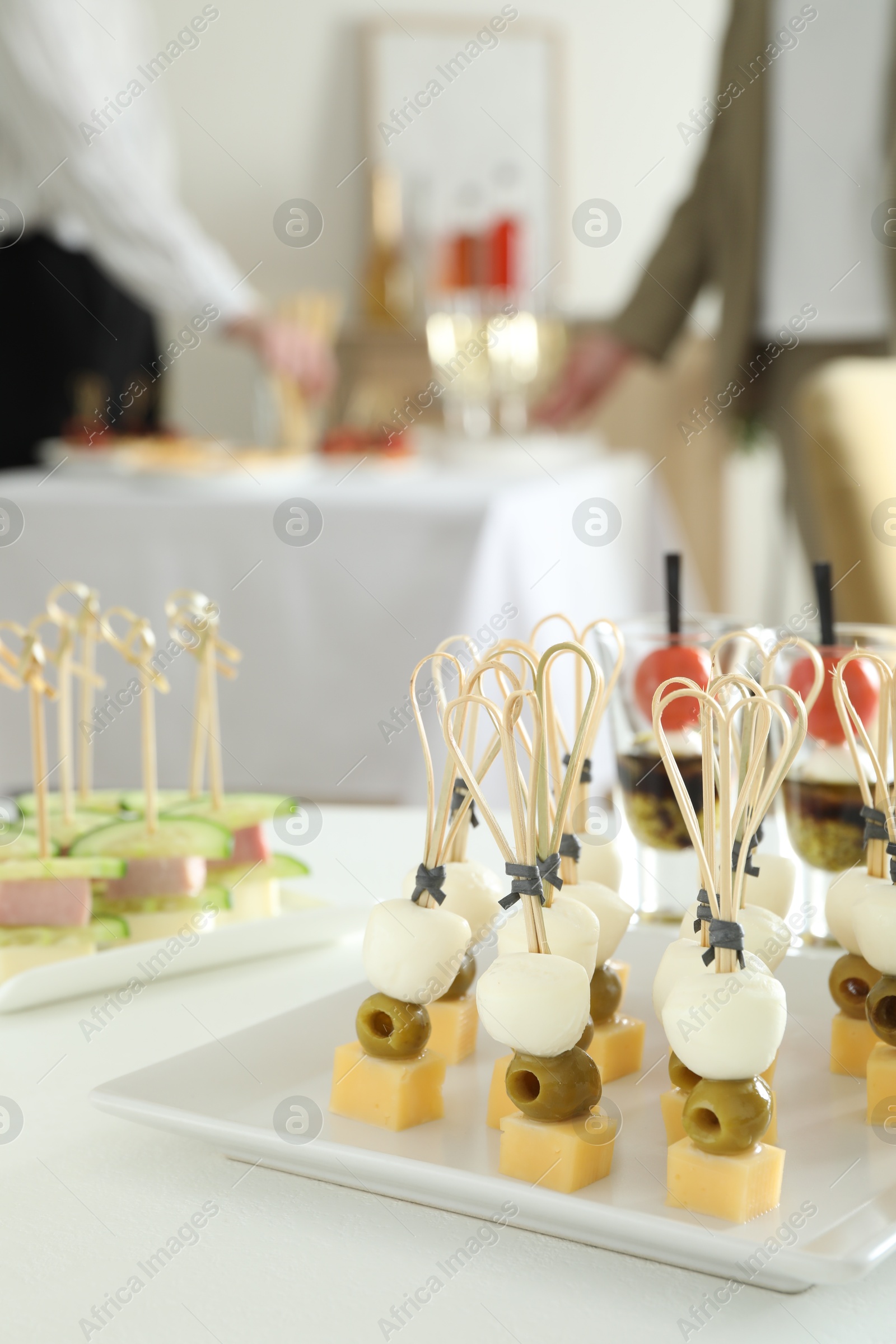 Photo of Many different tasty canapes on white table. People enjoying buffet meals indoors, closeup