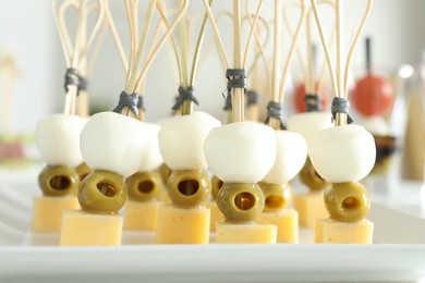 Photo of Tasty canapes with different types of cheese and green olives on white table, closeup