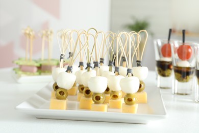 Photo of Many different tasty canapes on white table indoors