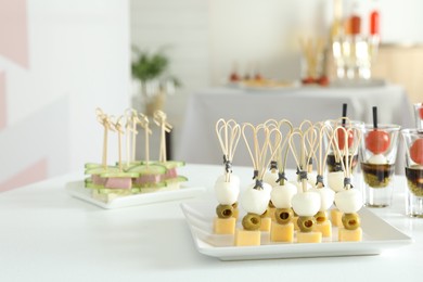 Photo of Many different tasty canapes on white table indoors