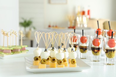 Photo of Many different tasty canapes on white table indoors