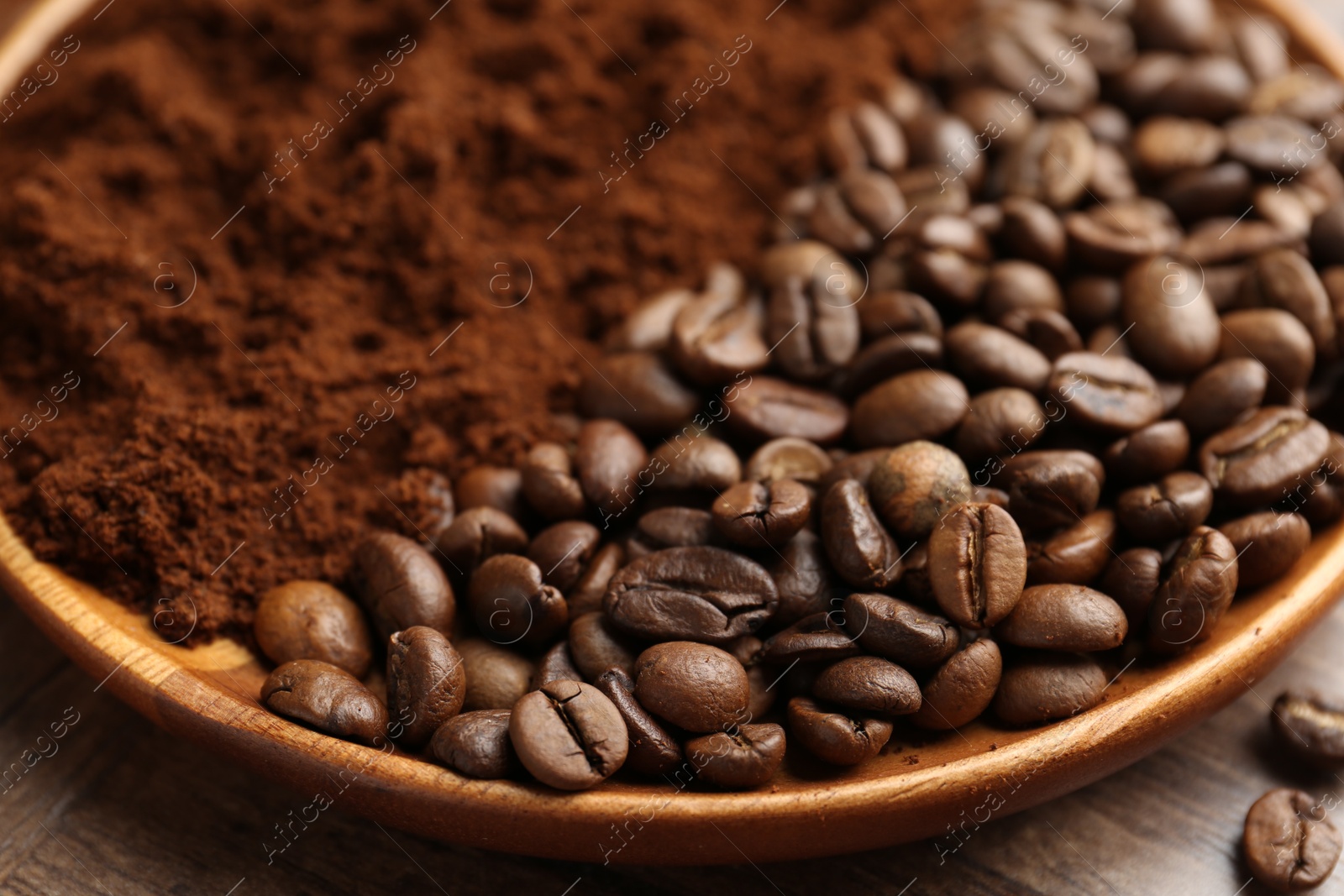 Photo of Ground coffee and roasted beans in bowl on wooden table, closeup