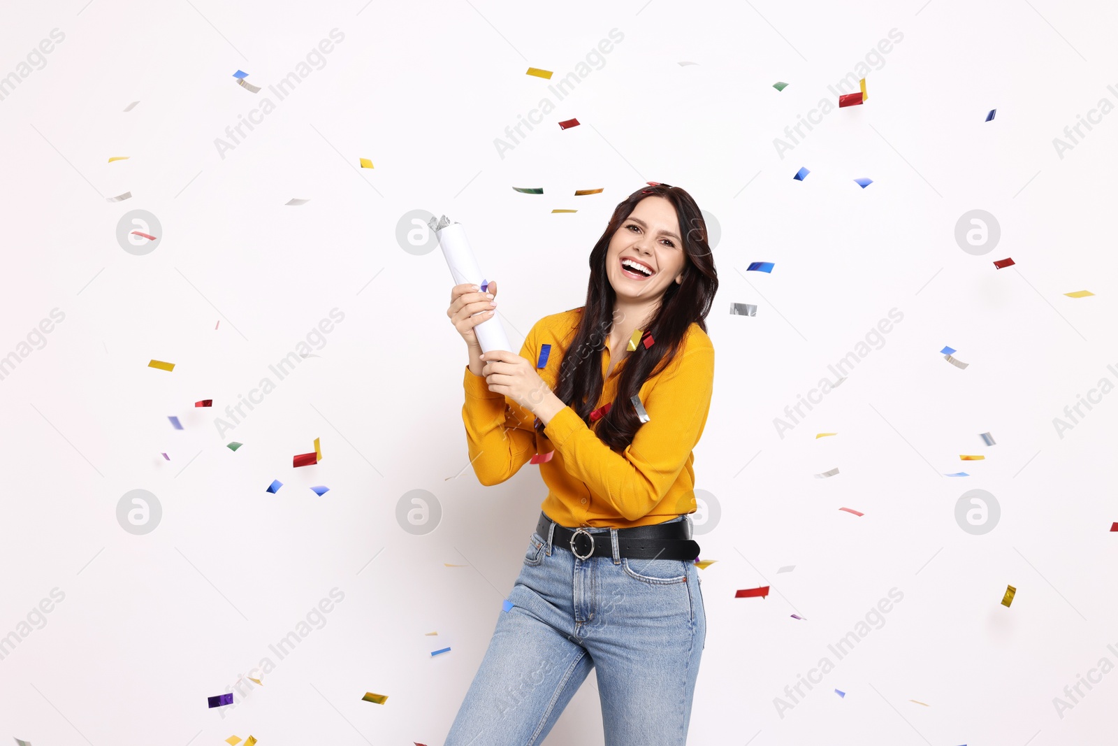 Photo of Happy woman blowing up confetti popper on white background. Surprise party