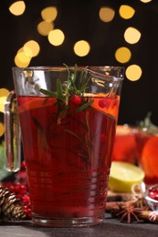 Photo of Tasty punch drink in glass jug on dark table against blurred lights, closeup