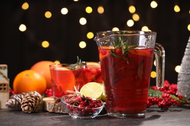 Photo of Tasty punch drink and ingredients on dark table against blurred lights