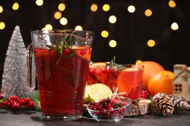 Photo of Tasty punch drink and ingredients on dark table against blurred lights