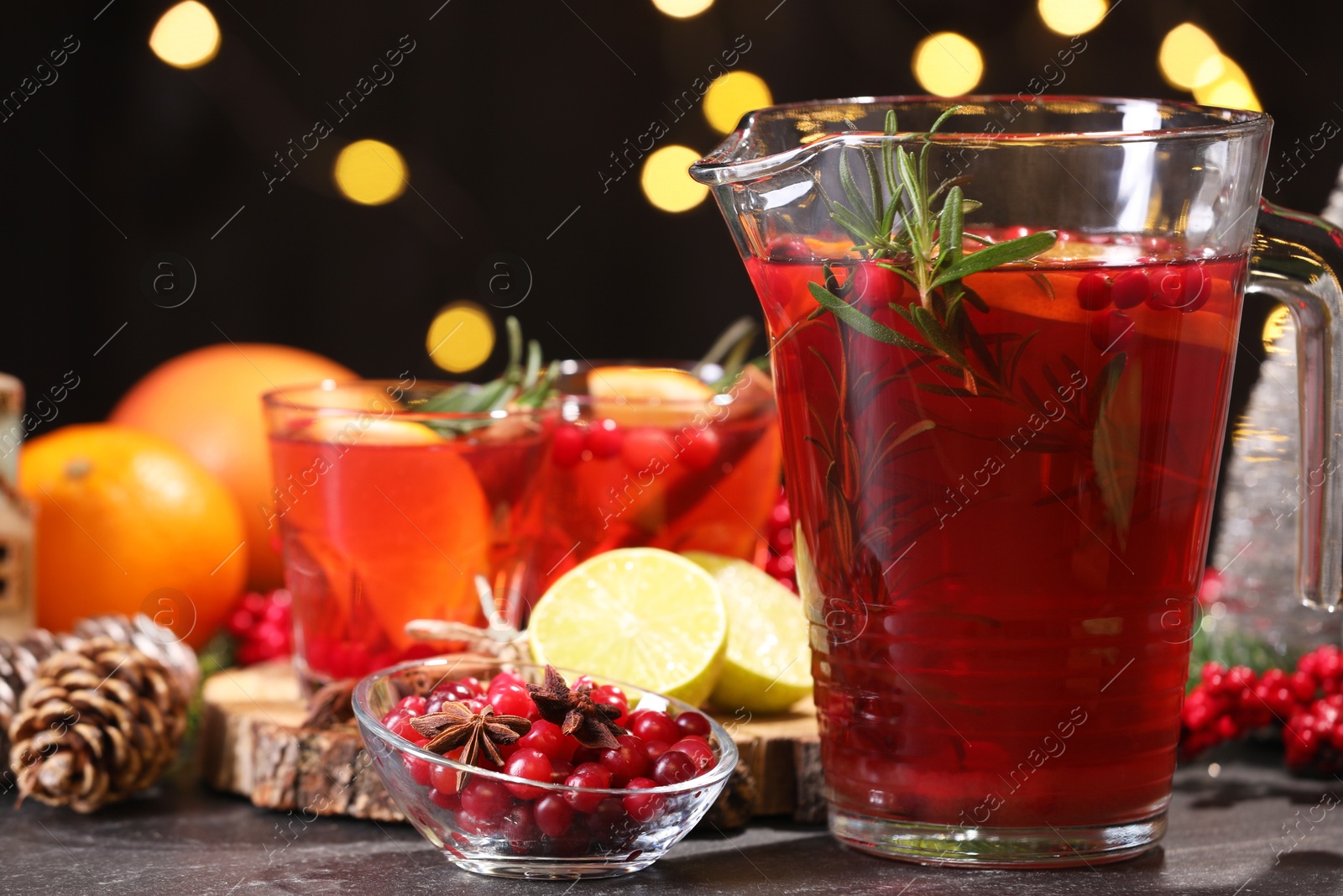 Photo of Tasty punch drink and ingredients on dark table against blurred lights, closeup