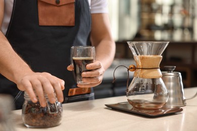 Barista with aromatic filter coffee at table in cafe, closeup