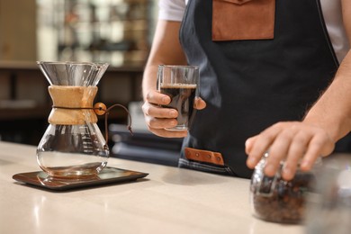 Photo of Barista with aromatic filter coffee at table in cafe, closeup