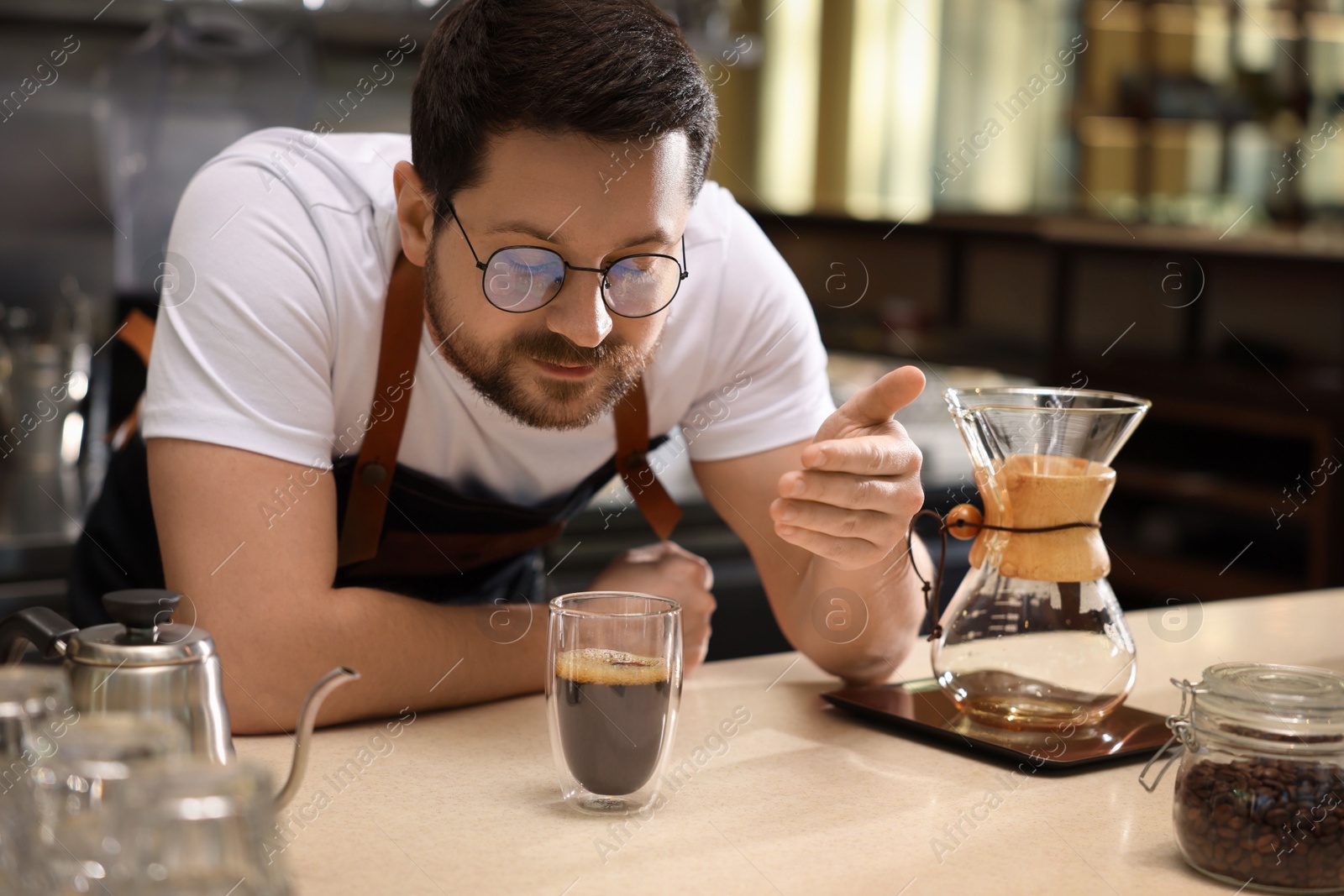 Photo of Barista sniffing aromatic filter coffee at table in cafe