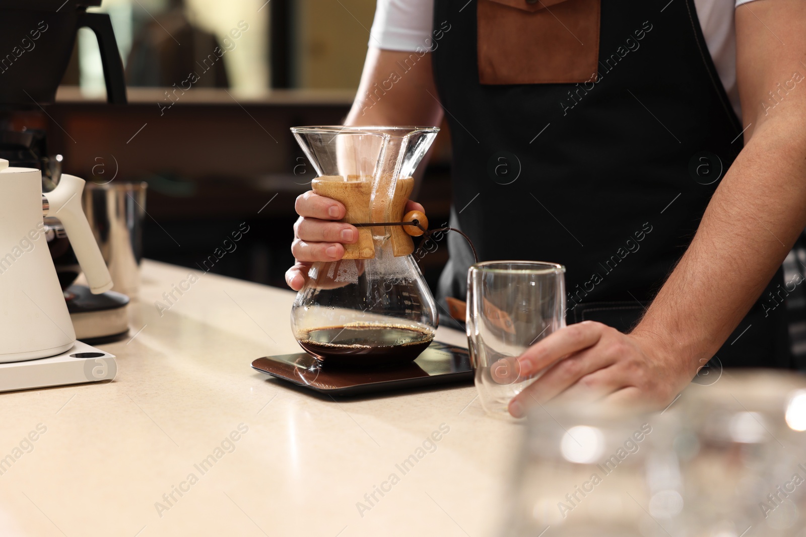 Photo of Barista with glass coffeemaker at table in cafe, closeup