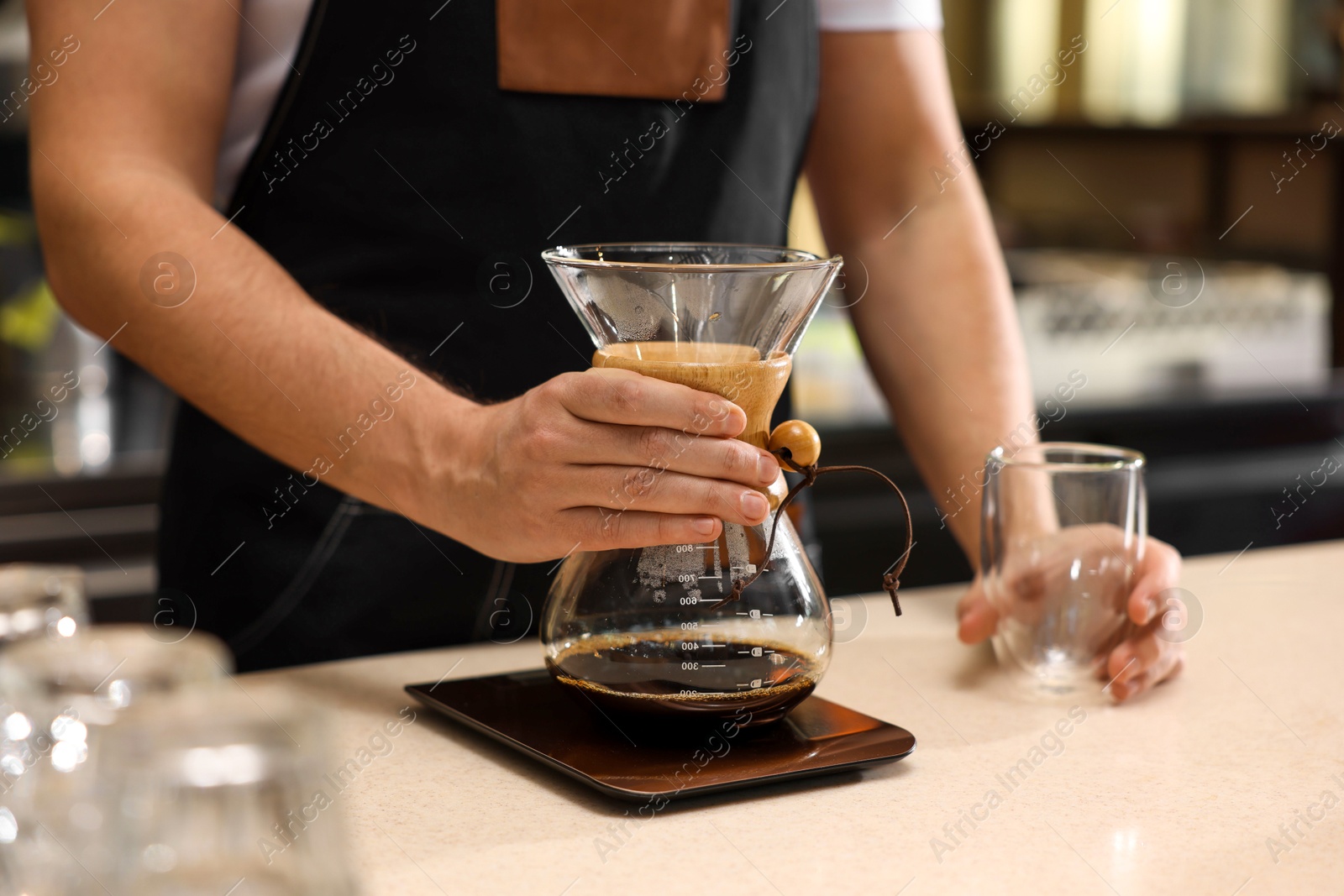 Photo of Barista with glass coffeemaker at table in cafe, closeup