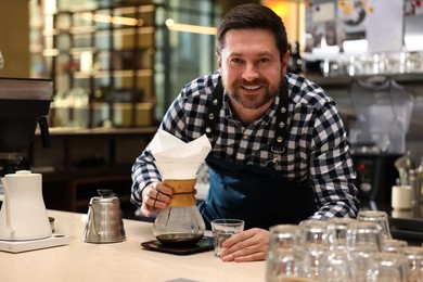 Photo of Barista with glass coffeemaker at table in cafe