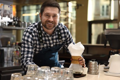 Photo of Barista with glass coffeemaker at table in cafe