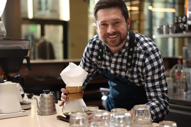 Photo of Barista with glass coffeemaker at table in cafe