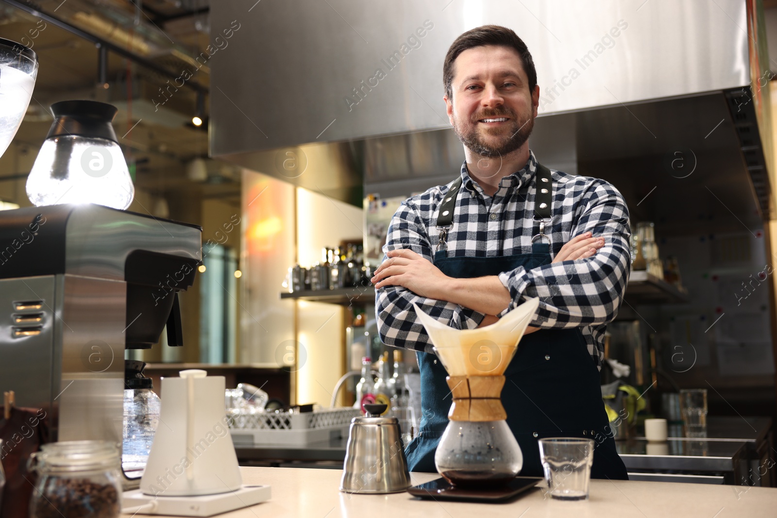 Photo of Barista with glass coffeemaker at table in cafe