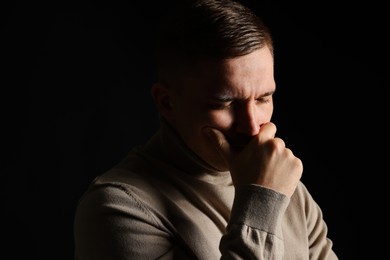 Photo of Distressed young man crying on black background