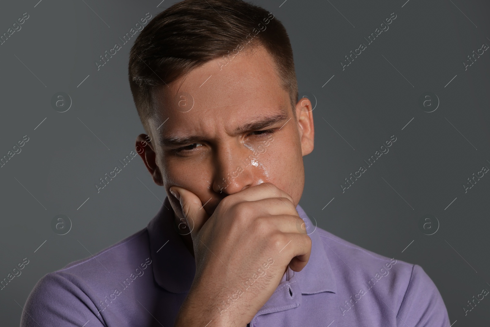 Photo of Distressed young man crying on grey background