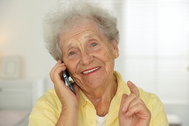 Photo of Smiling senior woman talking on smartphone indoors