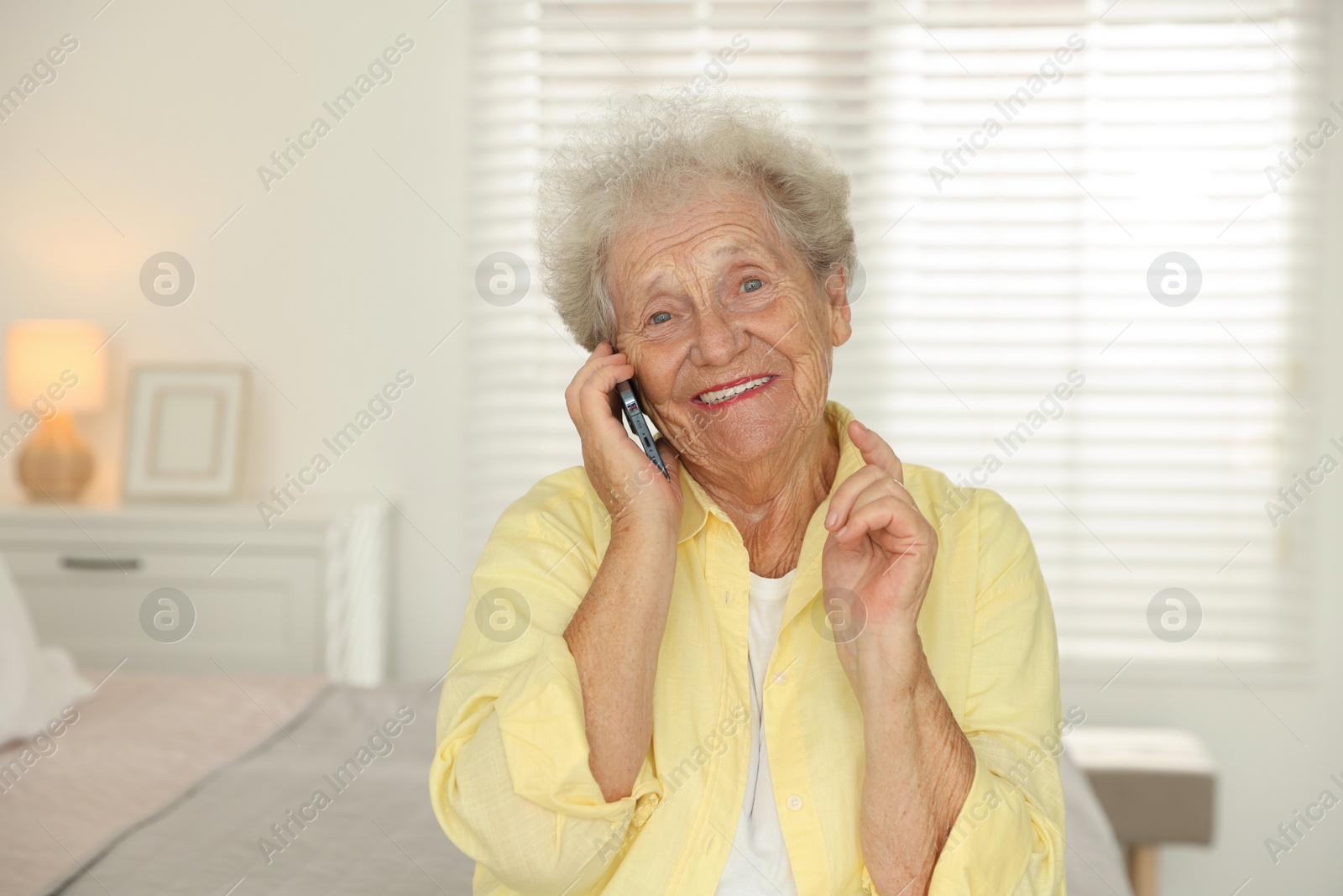 Photo of Smiling senior woman talking on smartphone at home