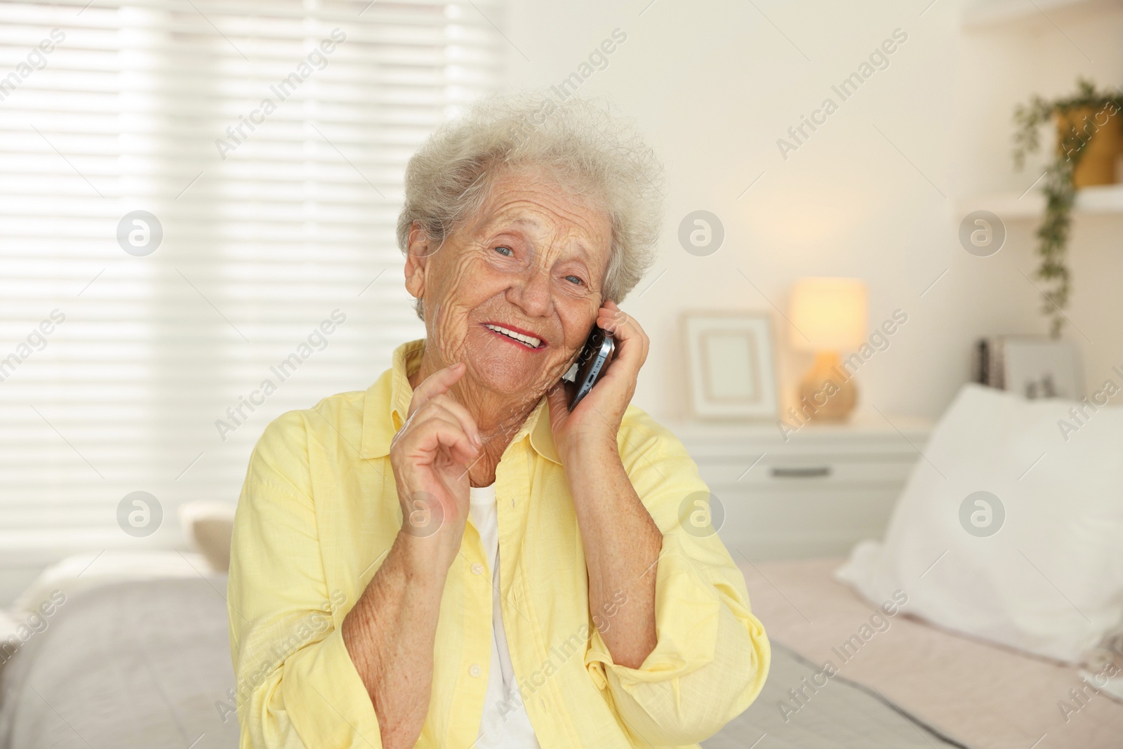 Photo of Smiling senior woman talking on smartphone at home