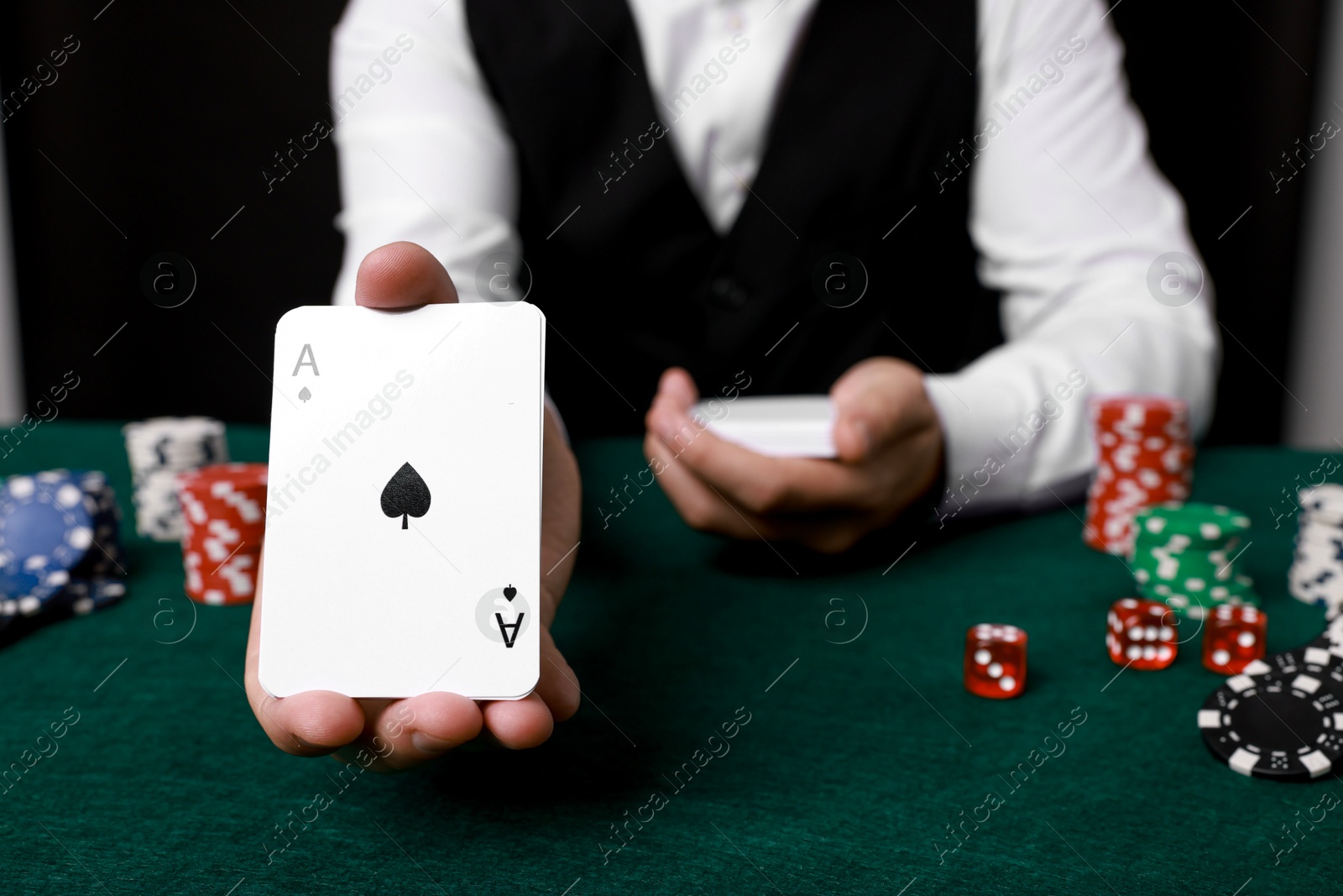 Photo of Professional croupier with playing cards at gambling table, closeup