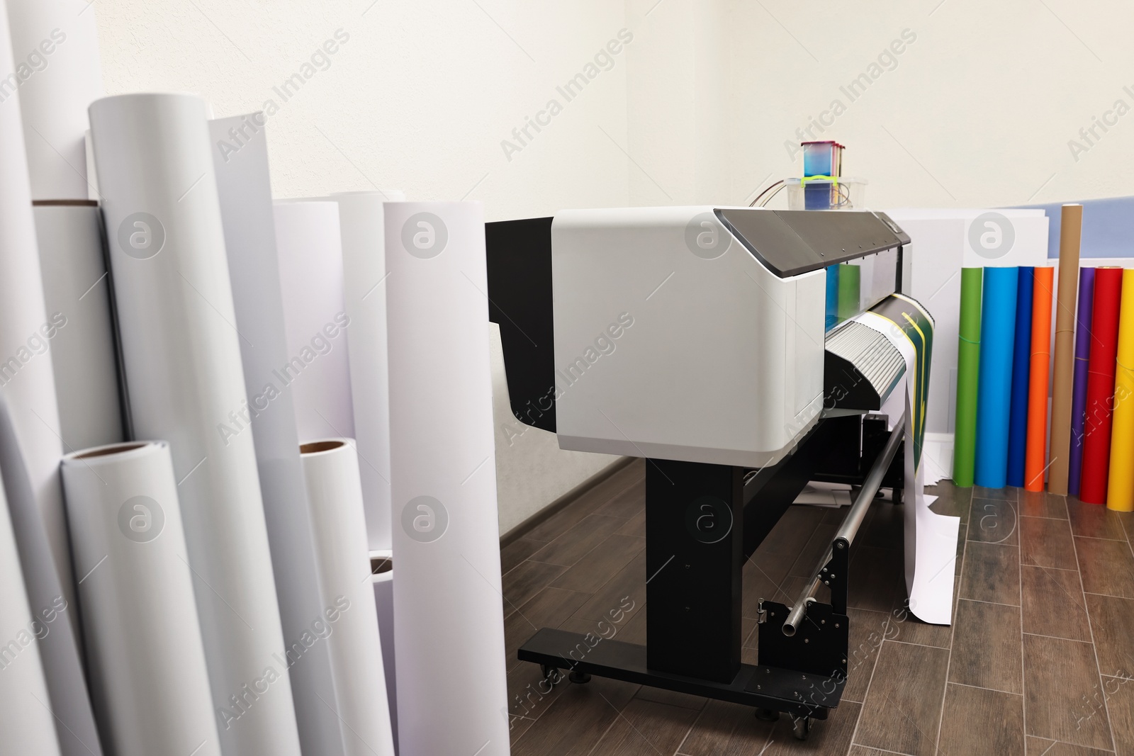 Photo of Wide-format printer and paper rolls indoors. Printing house