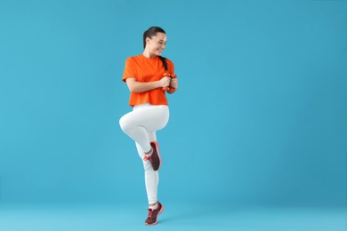 Photo of Woman exercising with dumbbells on light blue background, space for text