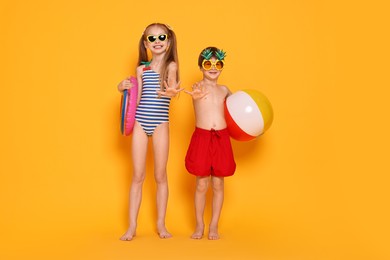 Photo of Happy little kids in beachwear on orange background