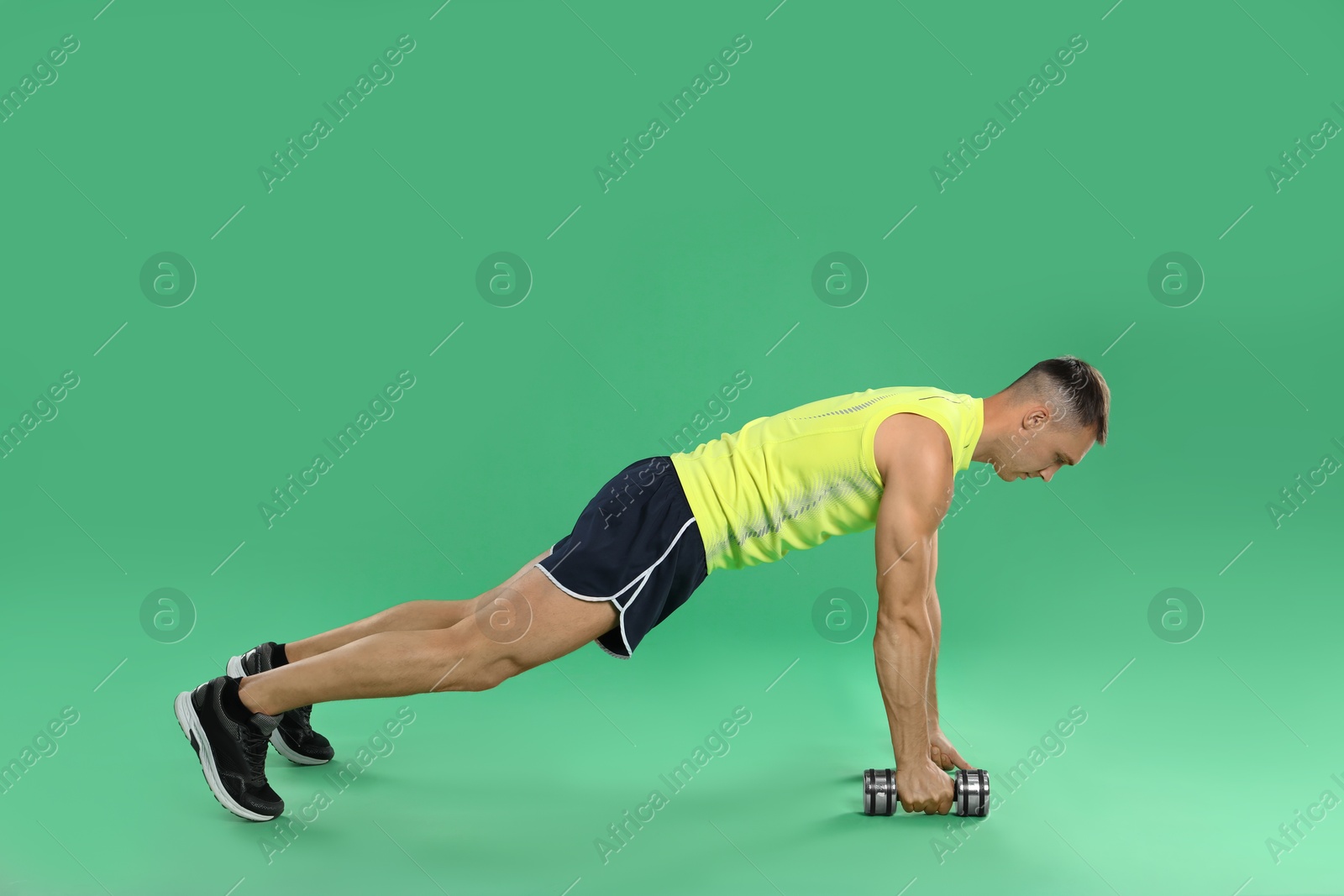 Photo of Man exercising with dumbbell on green background