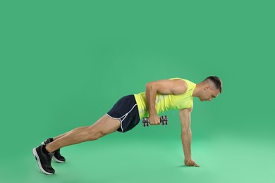 Photo of Man exercising with dumbbell on green background