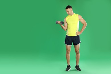 Man exercising with dumbbell on green background, space for text