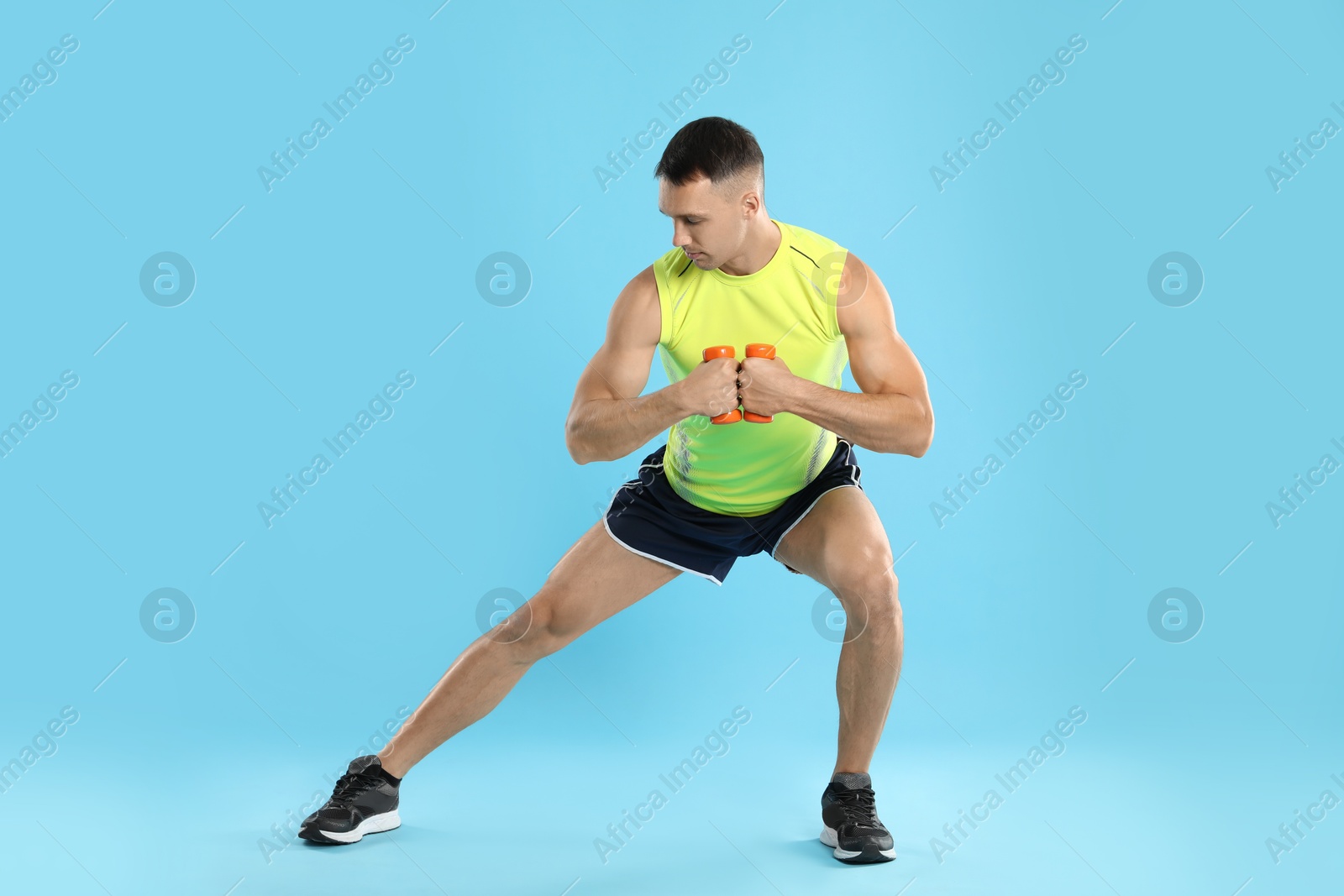 Photo of Man exercising with dumbbells on light blue background