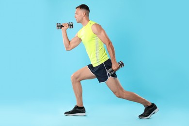 Man exercising with dumbbells on light blue background