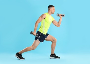 Photo of Man exercising with dumbbells on light blue background