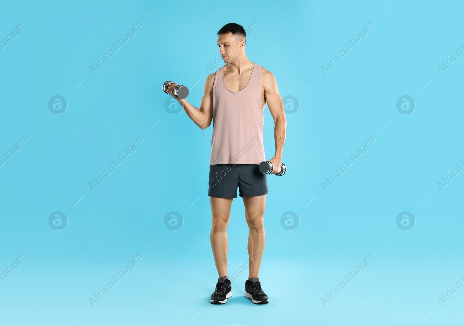 Photo of Man exercising with dumbbells on light blue background