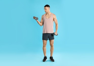 Photo of Man exercising with dumbbells on light blue background