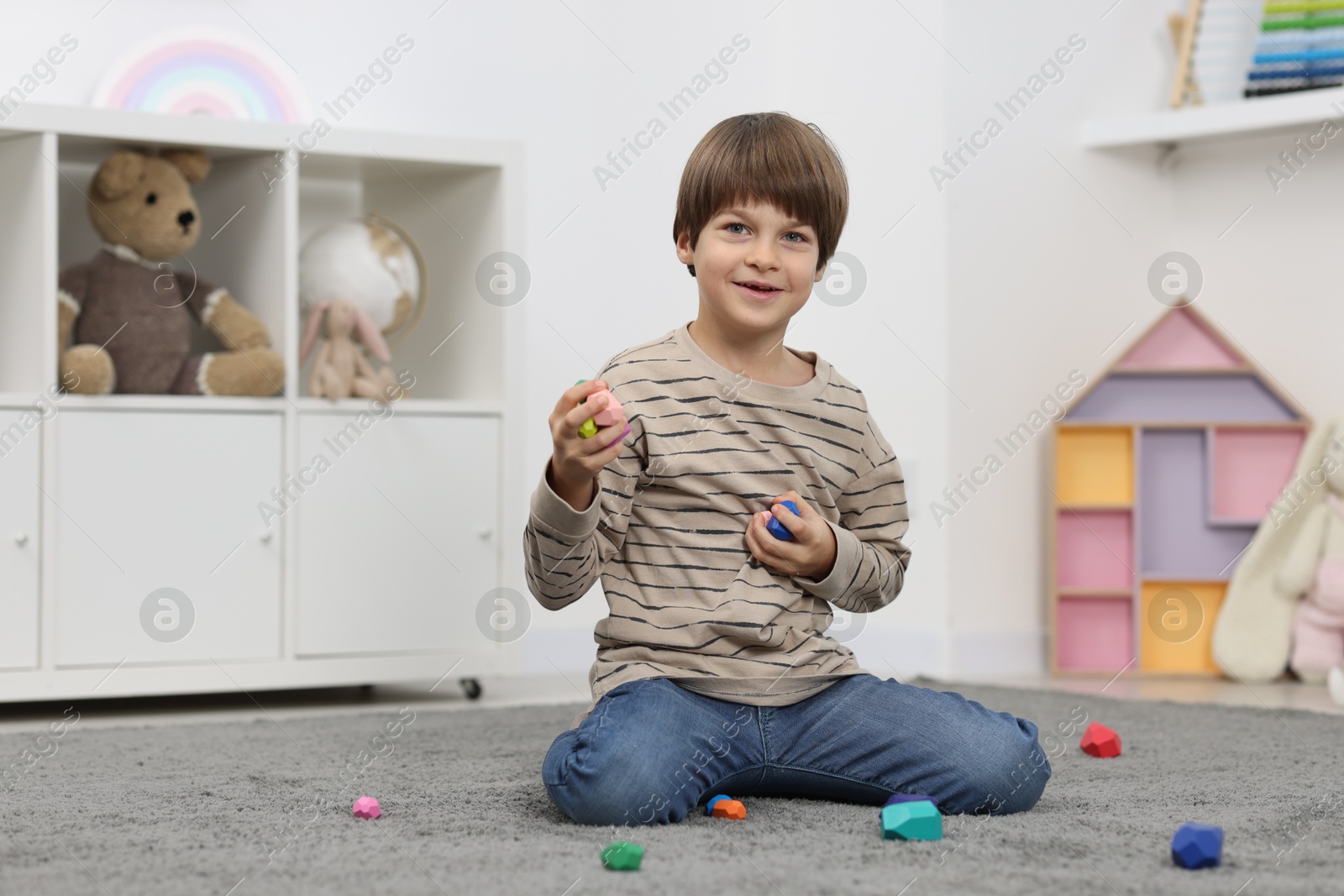 Photo of Boy playing with balancing stones on floor indoors