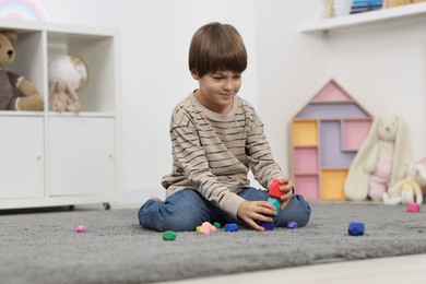 Photo of Boy playing with balancing stones on floor indoors