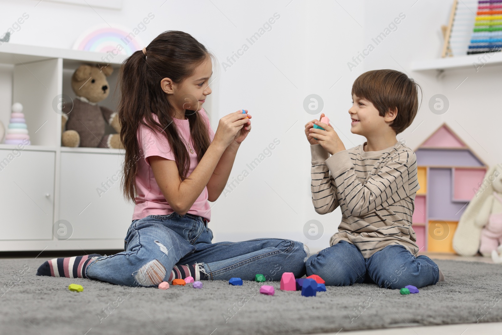 Photo of Children playing with balancing stones on floor indoors