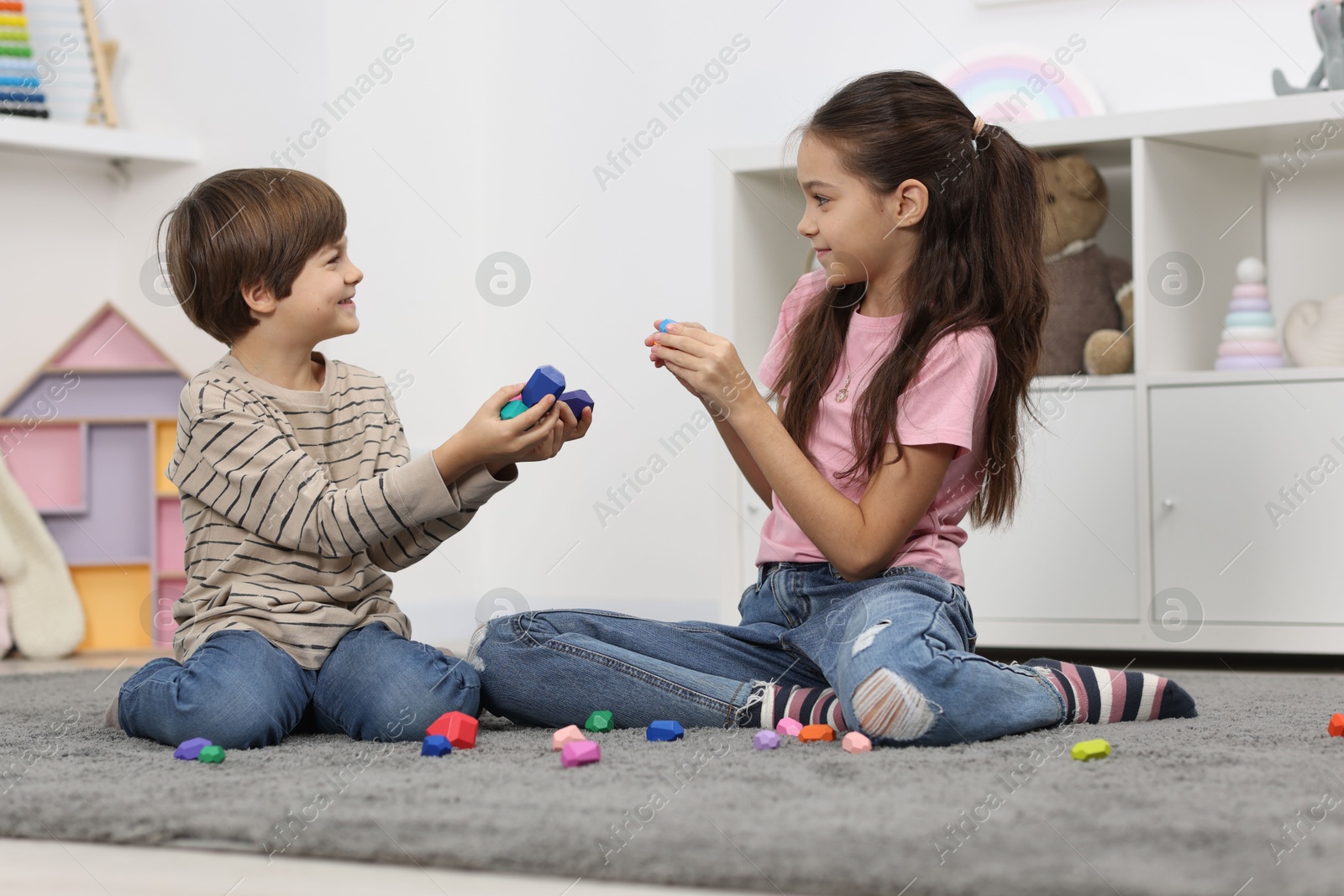 Photo of Children playing with balancing stones on floor indoors