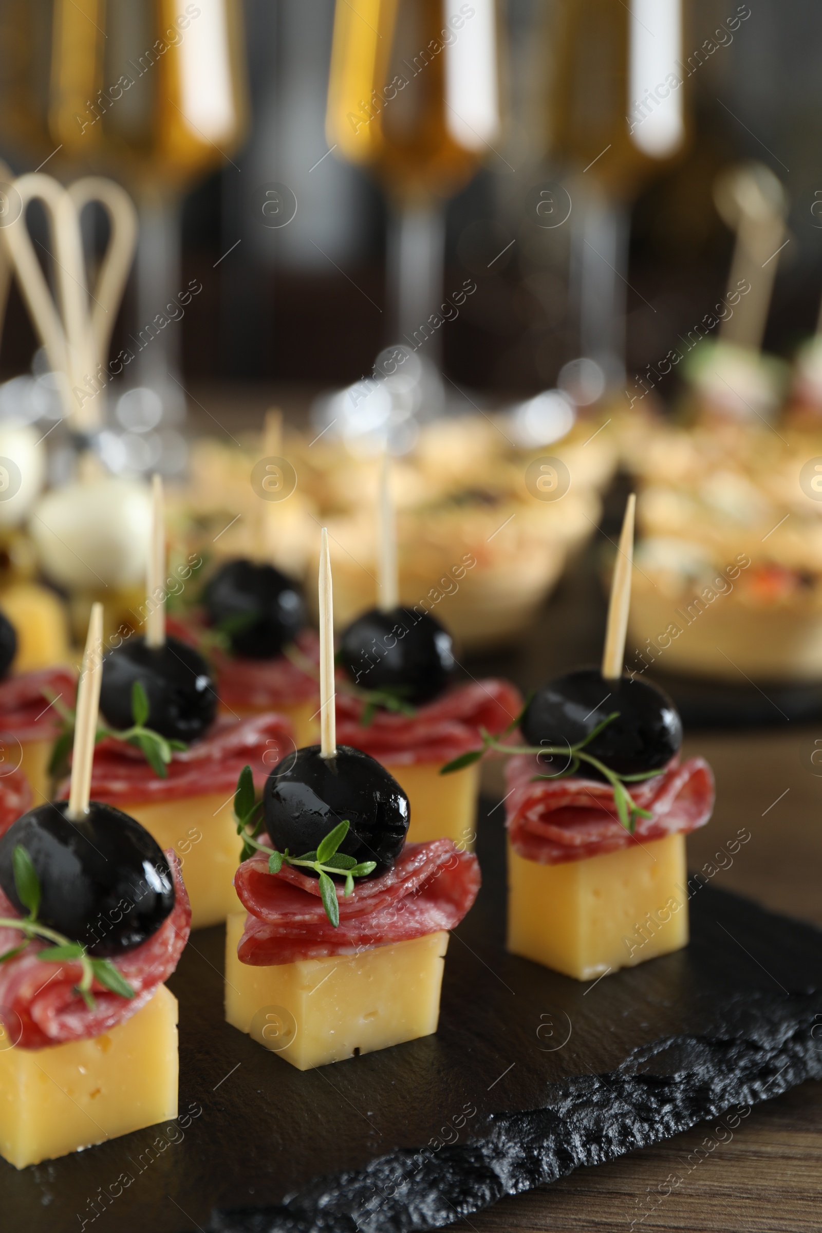 Photo of Tasty canapes with cheese, black olives and salami on table, closeup