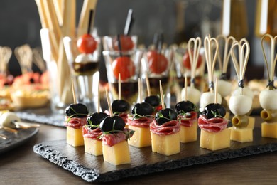 Photo of Many different tasty canapes on wooden table, closeup