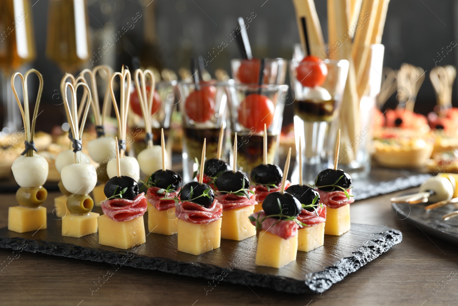 Photo of Many different tasty canapes on wooden table, closeup