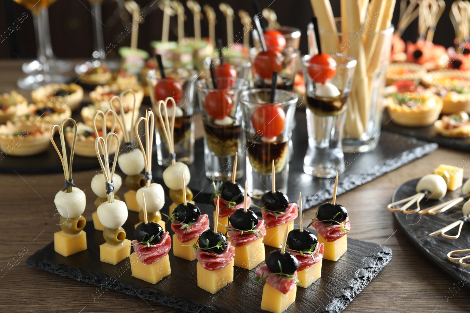 Photo of Many different tasty canapes on wooden table, closeup