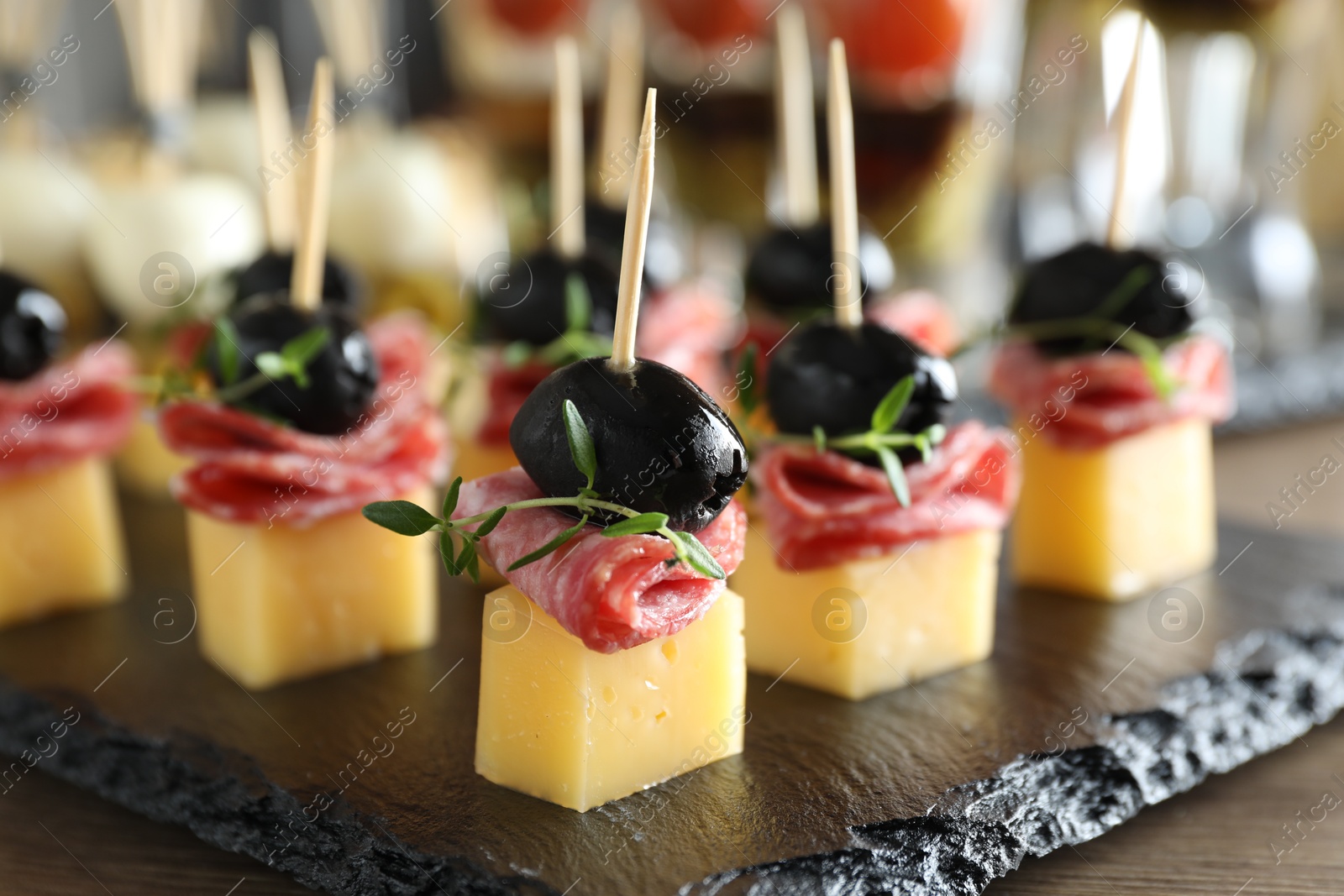 Photo of Tasty canapes with cheese, black olives and salami on table, closeup