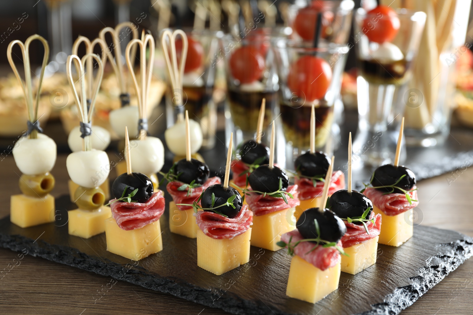 Photo of Many different tasty canapes on wooden table, closeup